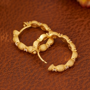 Vintage brushed gold hoop earrings with white zircon accents on brown leather surface