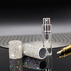 Detail of a 10ml rhinestone perfume spray bottle with silver nozzle on a reflective surface