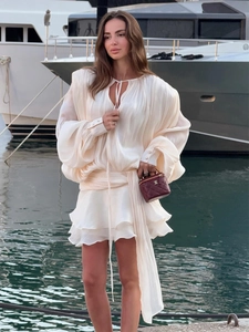 Detail of white long sleeve chiffon dress with ruffle hem and lantern sleeves on a yacht