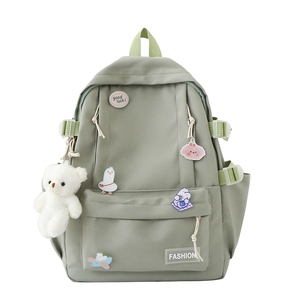 Pastel green school backpack with cute cartoon pins and a plush bear pendant