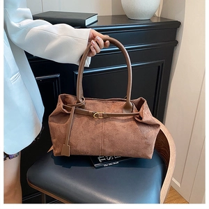 Close-up of brown suede tote bag with matte texture and elegant gold buckle detail