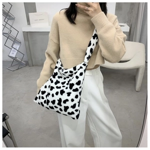 Detail of soft plush tote bag with cow print pattern worn by model in autumn style