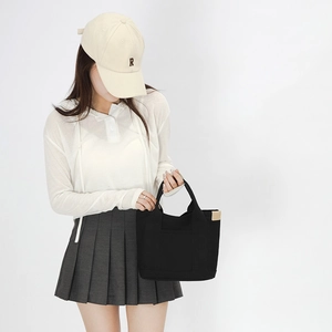 Minimalist black canvas tote bag shown in a lifestyle studio shot with casual styling