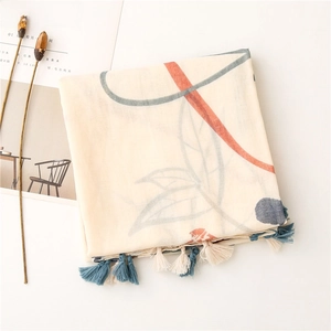 Detail of beige scarf with floral print and fringe tassels on a minimalist background