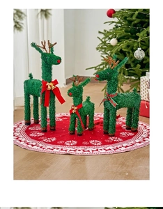 Three-piece set of dark green Christmas reindeer decorations with red bows on a tree skirt
