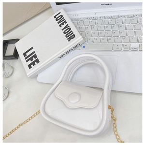 Mini white jelly bag with gold chain strap shown on a laptop for size reference