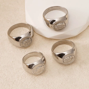Detailed close-up of four silver stainless steel signet rings with crest engravings