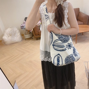 Détail du sac bandoulière en toile blanche avec motifs floraux bleus dessinés à la main