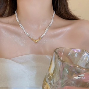 Elegant twisted pearl necklace with a polished gold heart pendant worn by a model