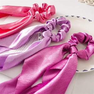 Detailed view of satin silk hair scrunchies with long ribbons in pink and purple shades