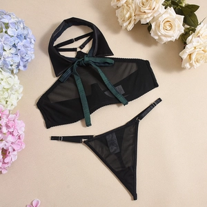 Detail of black mesh lingerie top with green bow and matching thong on floral background