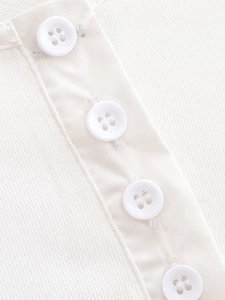 Macro detail of white buttons and textured knit fabric on a batwing sleeve dress