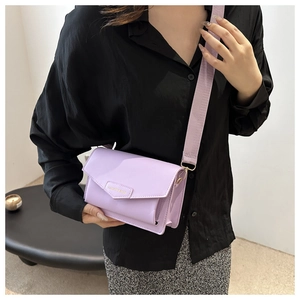 Detail of lavender flap crossbody bag with fashion gold lettering and woven strap