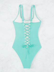 Detail view of lace-up back design on mint green one-piece swimsuit with marble background