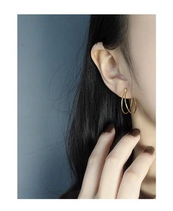 Detailed close-up of a model wearing elegant gold double-hoop minimalist earrings