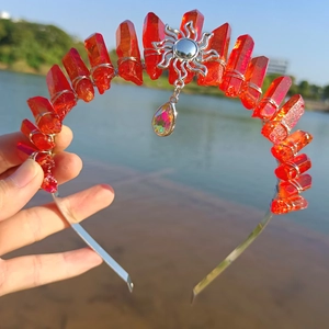 Detailed view of red crystal crown headband with silver sun charm and rainbow teardrop gem