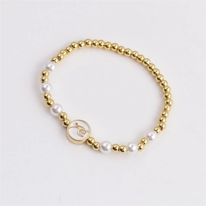 Goldenes Perlenarmband mit weißen Perlen und Buchstaben-Anhänger auf weißem Grund