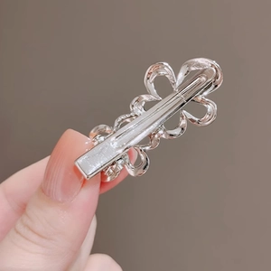 Close-up of silver metal alloy hair clip with hollow floral and clover pattern design