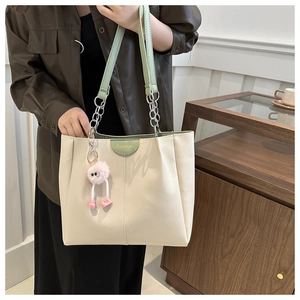 Dettaglio borsa shopper beige e verde con tracolla a catena e ciondolo rosa