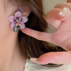 Élégantes boucles d'oreilles fleur en tissu violet avec perles de cristal sur modèle