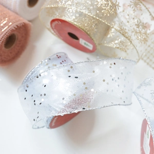 Close-up of sparkling silver sequins on white sheer chiffon ribbon for Christmas decor