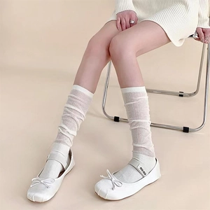 Nahaufnahme von Mary-Jane-Schuhen im Ballett-Stil mit Schleifen und Socken in Off-White