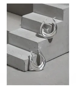 Macro shot of triple-layer S925 sterling silver hoop earrings on a textured stone step