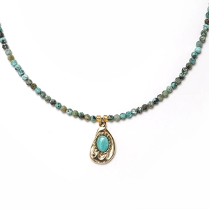 Detail of vintage sun and moon necklace with turquoise beads and gold teardrop pendant