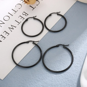 Detail of two pairs of black stainless steel hoop earrings in different sizes on blue background