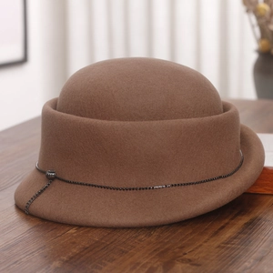 Detail of vintage brown wool bowler hat with beaded trim on a textured wooden table