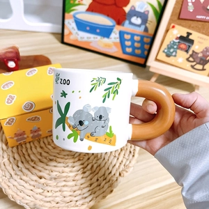 Close-up of ceramic koala mug with thick brown handle and yellow branded gift box