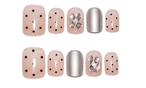 Detail of short press-on nails featuring nude pink polish, silver accents, and rhinestones
