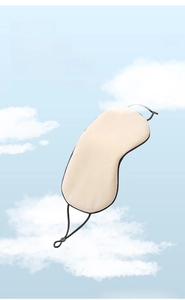 Close-up of beige ice silk sleep mask with adjustable ear straps against a blue sky