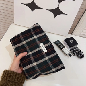 Detail of a vintage plaid cosmetic bag with simple wish label and hand-held styling
