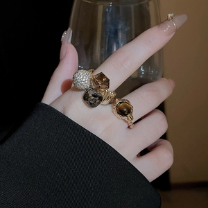 Detailed view of bohemian gold rings with smoky square crystal and tiger eye stone inlay