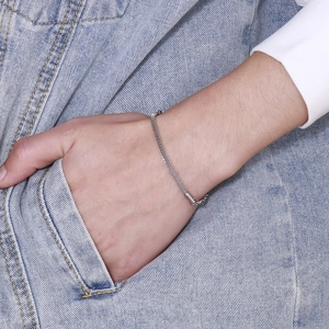 Detail of silver mesh chain bracelet worn on wrist against denim background