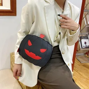 Detail of a black pumpkin crossbody bag with red embroidery and gold chain strap