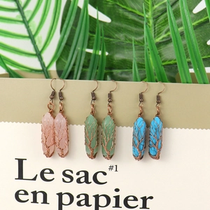 Detail of handmade wire wrapped crystal hexagon earrings with tree of life design