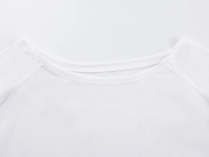 Close-up of raglan sleeve stitching and neckline on a minimalist white off-shoulder t-shirt