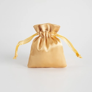 Close-up of golden satin drawstring gift bag showing smooth texture and fine silk ribbon detail