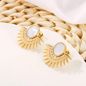 Gros plan de boucles d'oreilles dorées en forme d'éventail avec incrustation blanche