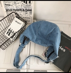 Detailed top view of a blue denim crescent crossbody bag with double zippers and minimal design