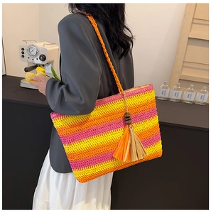 Detail of colorful striped straw tote bag with wood bead tassel and woven shoulder strap
