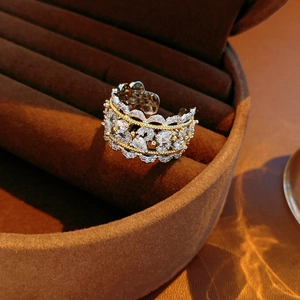 Macro shot of silver and gold hollow lace open ring with zircon inlay on velvet