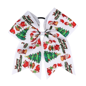 Detail of Christmas ribbon bow hair tie featuring Santa and tree patterns on white fabric