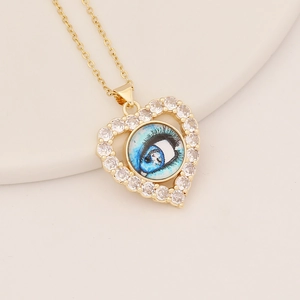 Close-up of golden heart pendant with a blue eye inlay and white cubic zirconia accents