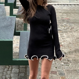 Dettaglio dell'abito in maglia nera con bordo a balze bianche e tessuto morbido