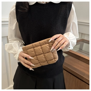 Khaki quilted down clutch bag held by a model to show size and soft puffy texture
