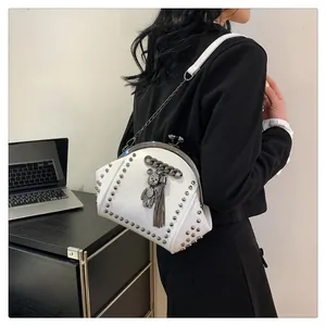 Detailed side view of white studded shell bag with diamond bear charm and metal chain