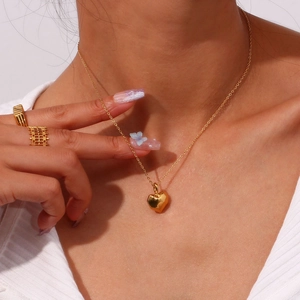 Close-up of a model wearing a gold necklace with a solid faceted heart pendant